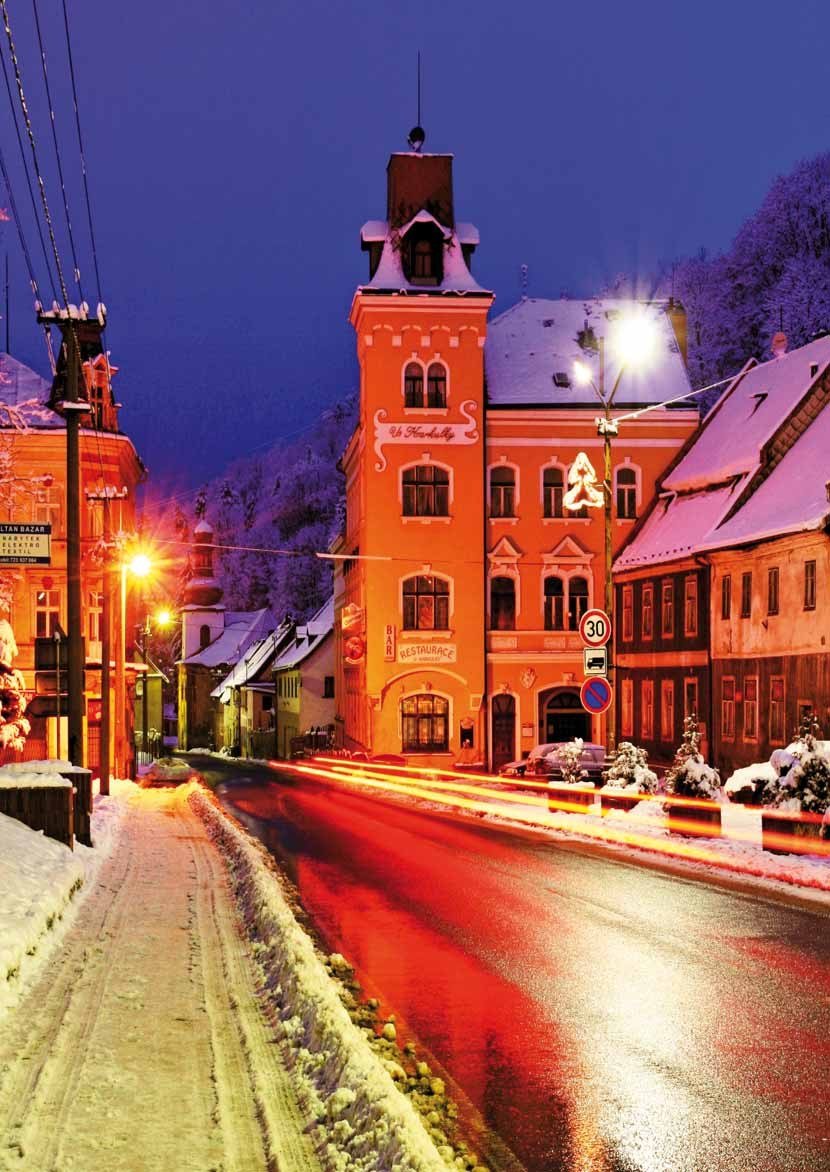 Noční zimní pohled na rozsvícenou historickou budovu města a zasněženou ulici (Slavkovský zpravodaj, 12/2014)