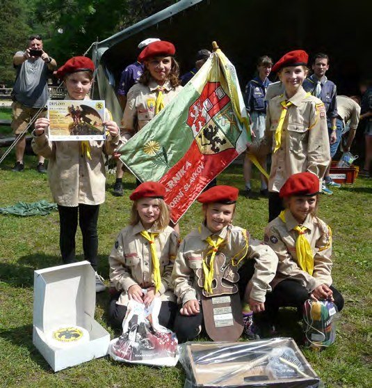 Slavkovští skauti s vlajkami na skautských závodech (Slavkovský zpravodaj, 7/2018)