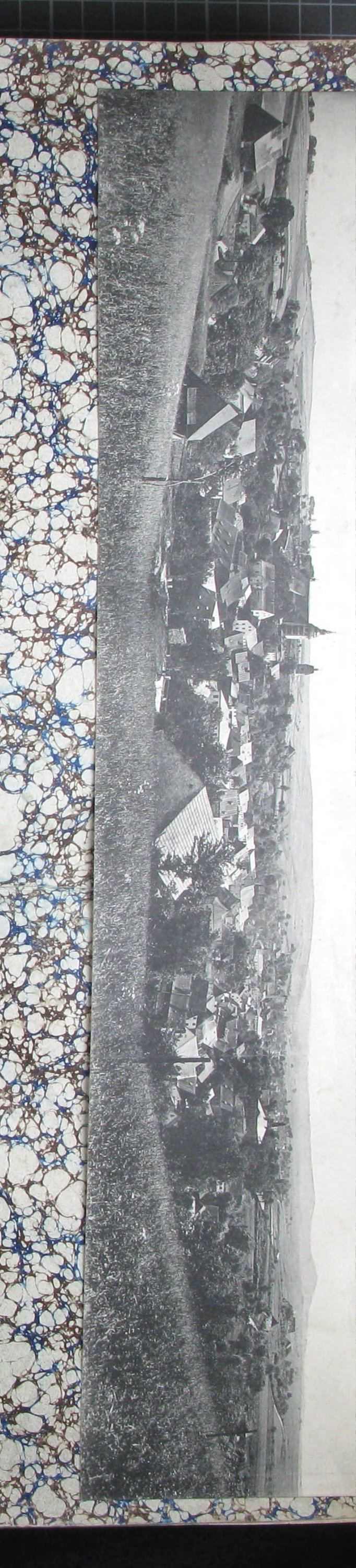 Panoramatický pohled na město Horní Slavkov (Schlaggenwald) s kostelními věžemi, loukami v popředí a kopci v pozadí; nalepená podlouhlá fotografie/pohlednice. Tištěná popiska: „Schlaggenwald, Panorama."