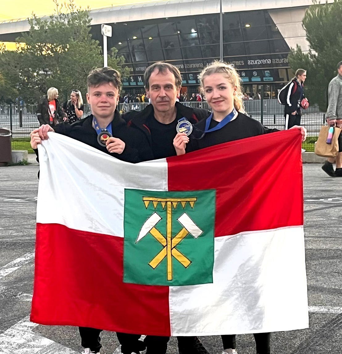 Mladí lidé s vlajkou se znakem města Horní Slavkov (Slavkovský zpravodaj, 1/2024)