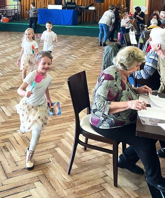 Děti s rodiči na akci v sále (Slavkovský zpravodaj, 4/2023)