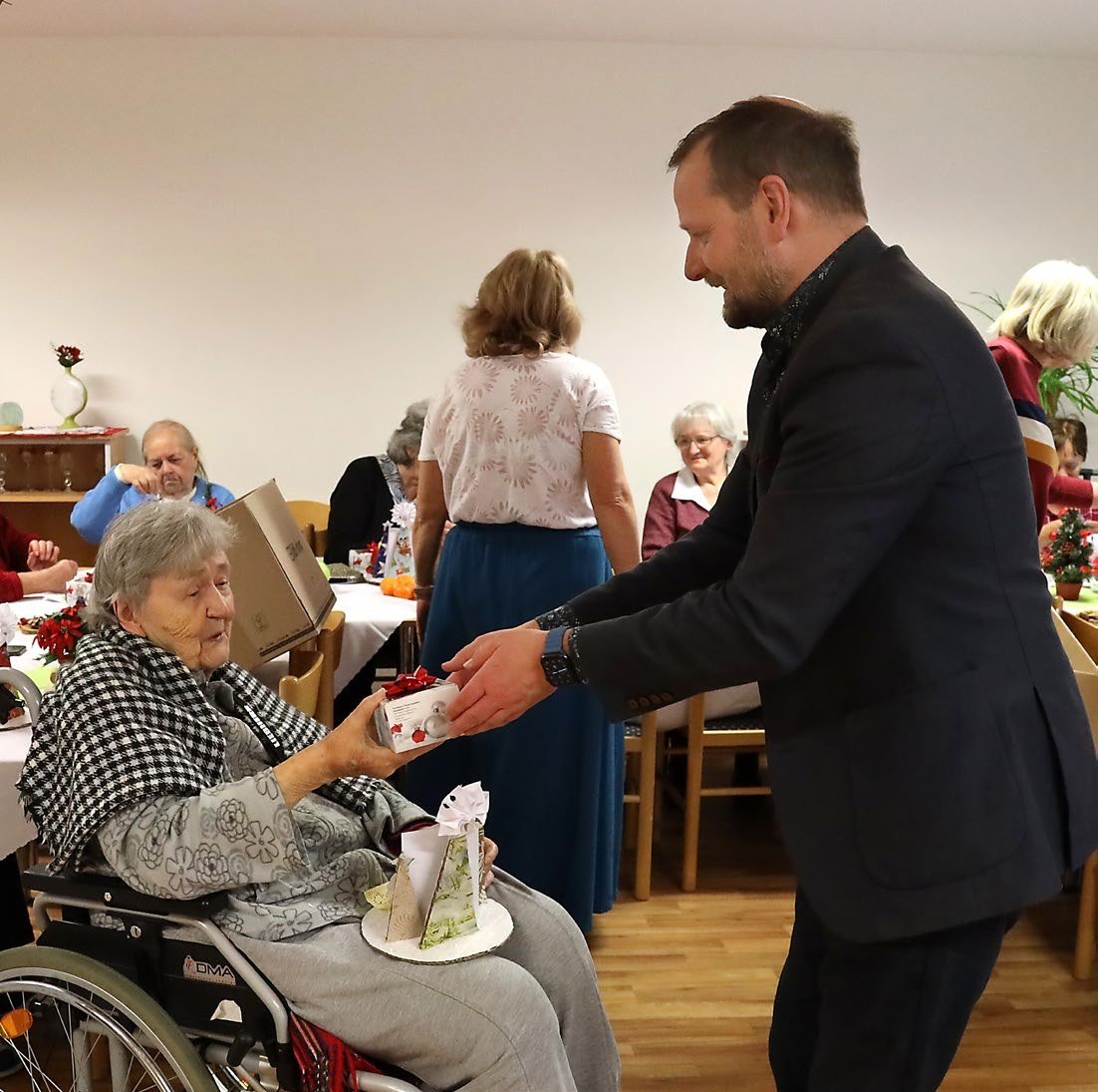 Starosta předává drobnou pozornost seniorům na vánočním posezení v domě s pečovatelskou službou (Slavkovský zpravodaj, 1/2024)