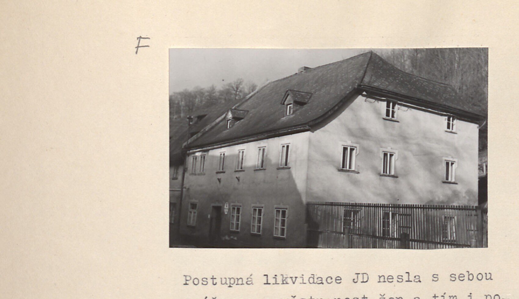 Patrový dům s omítanou fasádou v zástavbě (s lesem v pozadí) — patrně mateřská škola / objekt jeslí.