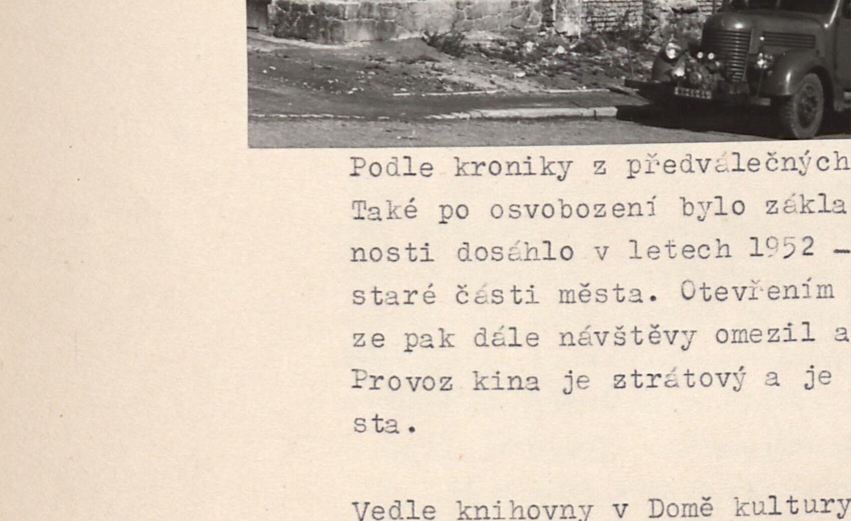 Budova staré požární zbrojnice (?) se starým nákladním autem / stříkačkou před ní.