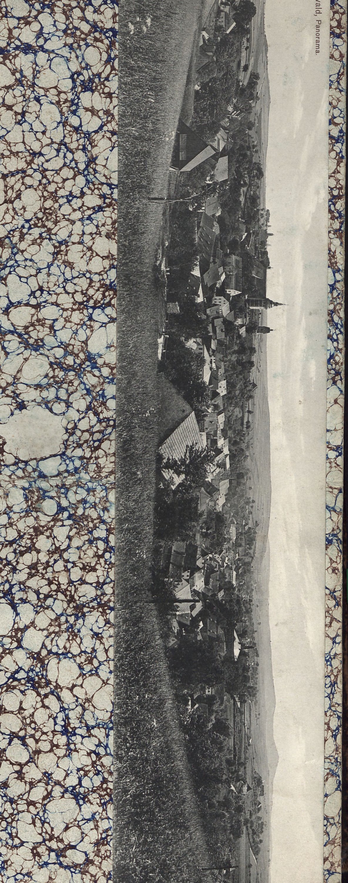 Panoramatická pohlednice Horního Slavkova (Schlaggenwald) — celkový pohled na město v krajině s farním kostelem s dvěma věžemi uprostřed, okolními domy, poli a zalesněnými kopci v pozadí. Tištěná popiska: „[Schlaggenw]ald. Panorama."