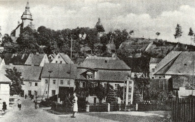 Pohled na náměstí (Zehentplatz) v Horním Slavkově (Schlaggenwald) s kostelem na kopci v pozadí, obklopeným stromy. V popředí měšťanské domy s vysokými štítovými střechami.