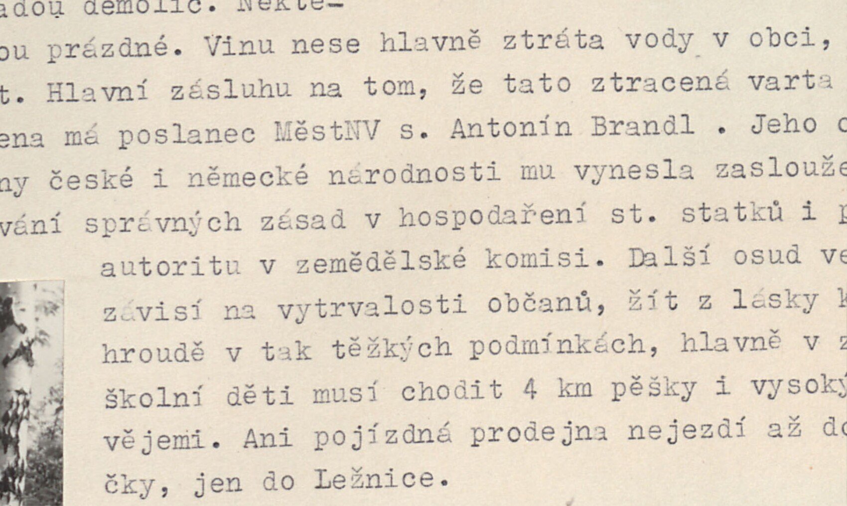 Pohled shora na horskou vesničku Ležnička s domky roztroušenými na zalesněném svahu/v údolí