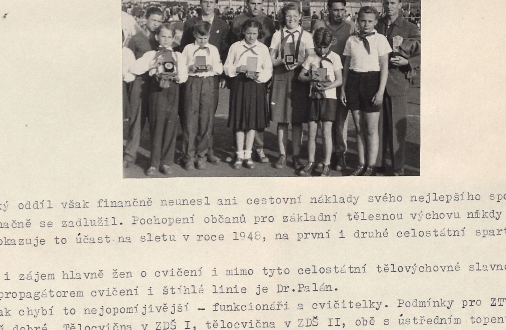 Černobílá fotografie: skupina mladých pionýrů a dětí (chlapci a dívky, někteří v pionýrských šátcích) držících ceny / diplomy — zřejmě ocenění mladí atleti po lehkoatletické soutěži.