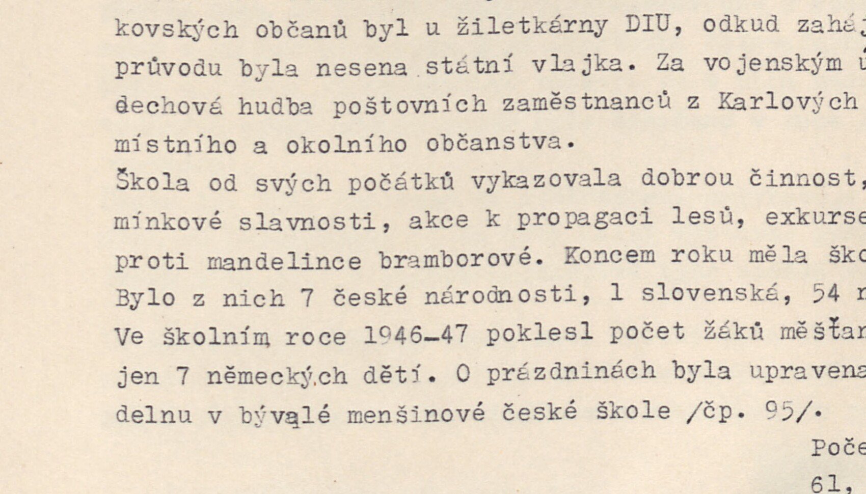 Patrový dům se sedlovou střechou v zástavbě (s lesem v pozadí) — patrně školní budova / dům spojený se školstvím.