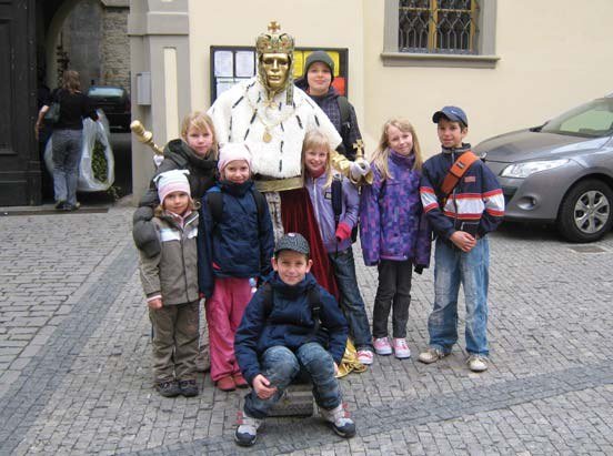 Skupina dětí s doprovodem před budovou na výpravě (Slavkovský zpravodaj, 5/2012)