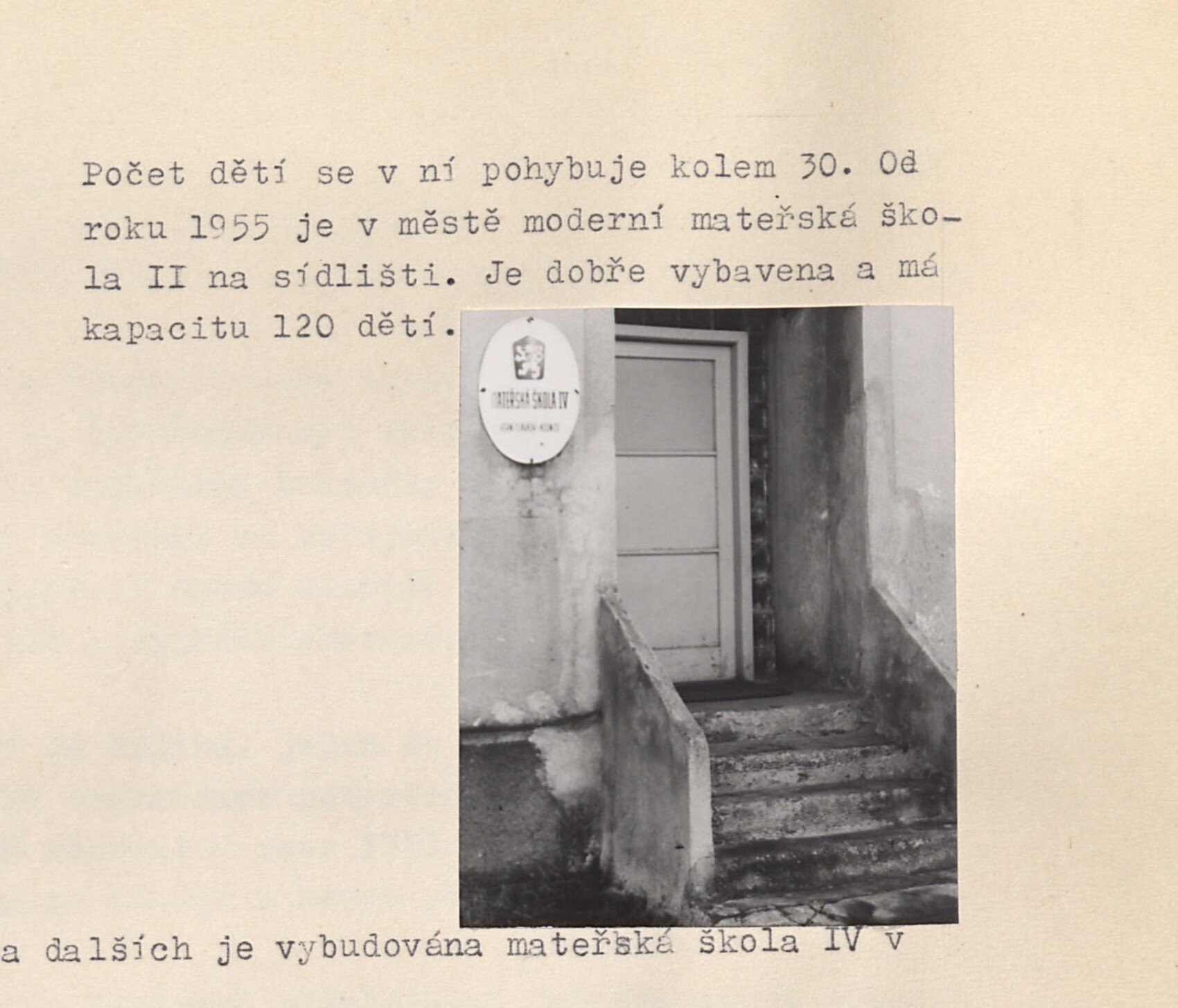 Vstupní schodiště a dveře budovy s kulatým smaltovaným znakem "Horní Slavkov" u vchodu (vchod mateřské školy II na sídlišti).