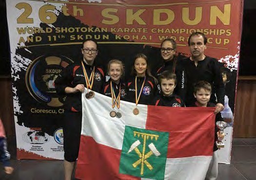 Slavkovští karatisté Champions teamu s medailemi a vlajkou na mistrovství v karate (Slavkovský zpravodaj, 1/2019)