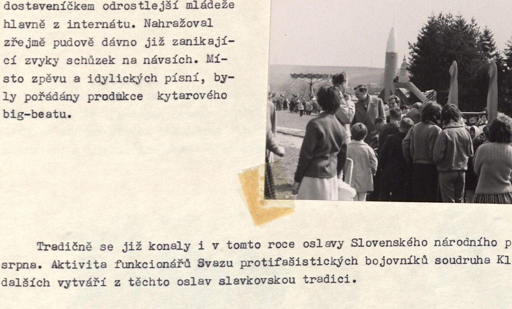 Shromáždění lidí v přírodě u pomníku/obelisku (v pozadí lesy) – pietní akt / oslava u pomníku.