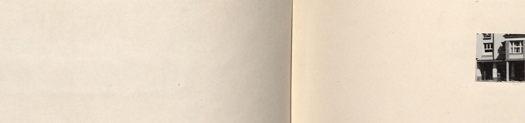 Panoramatický pohled na dlouhou patrovou budovu se sloupovým podloubím a obchody v přízemí (obchodní dům na sídlišti)